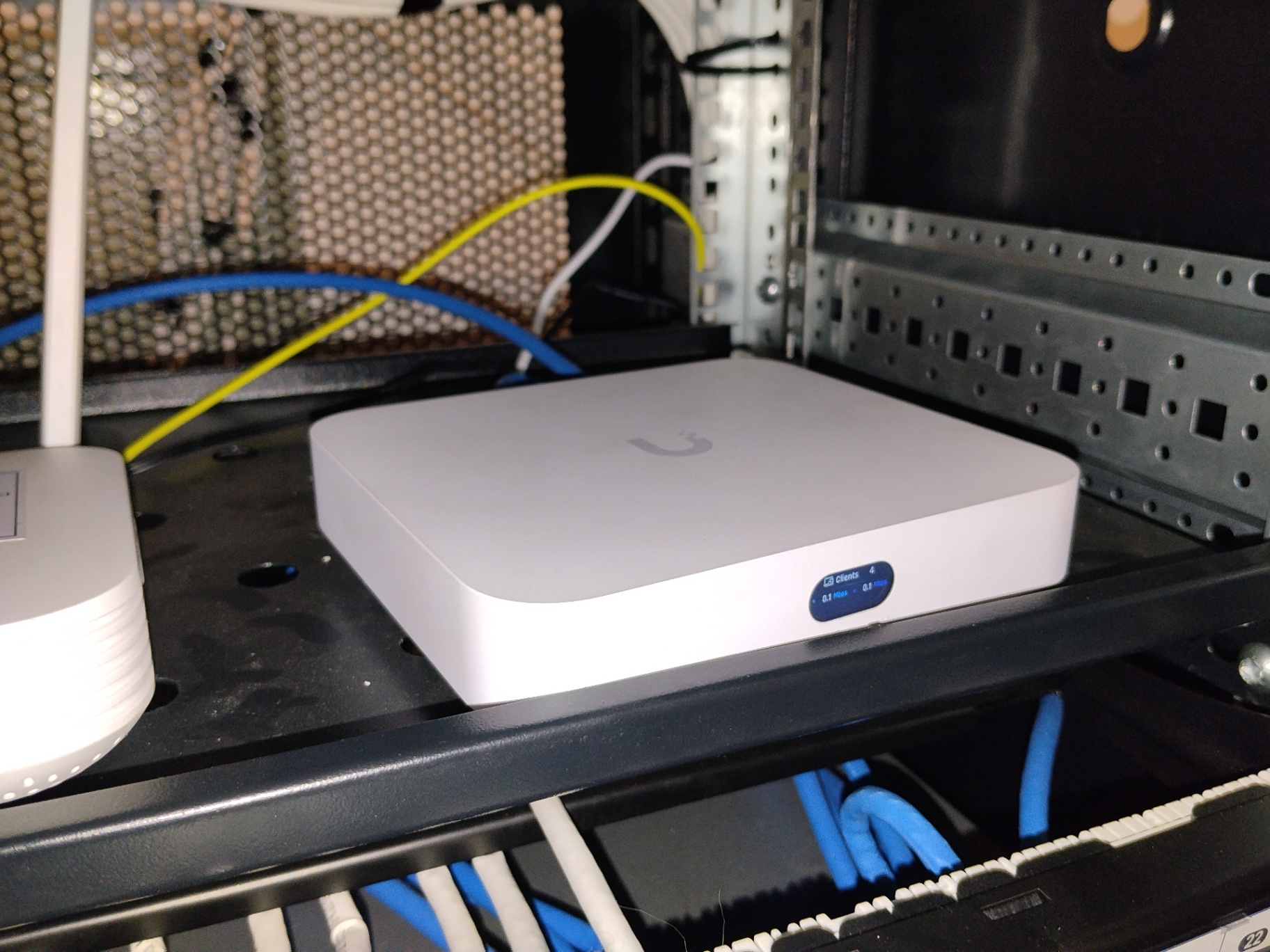 Gateway y switch Ubiquiti UniFi sobre bandeja de rack con patchcords azules